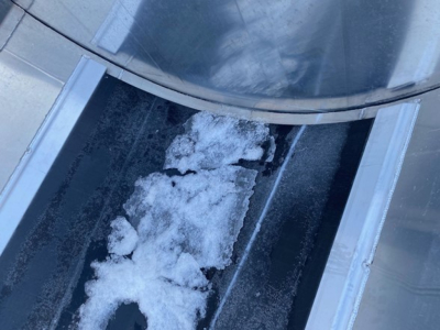 Dump trailer chute with snow accumulation showing interior surfaces and opening