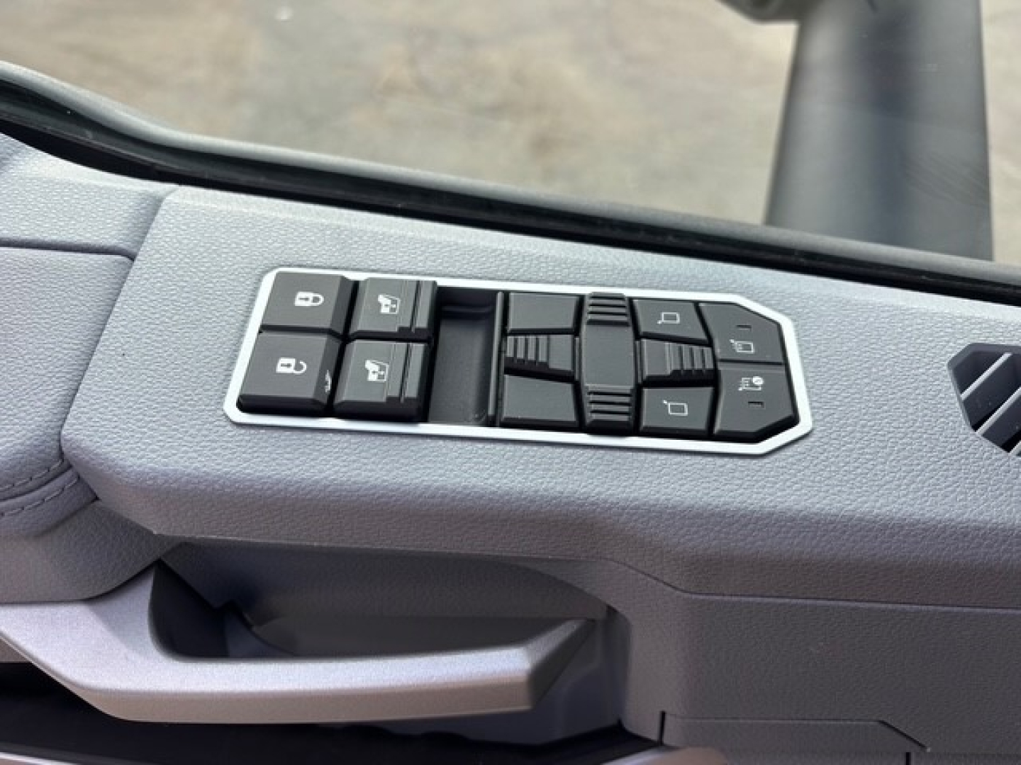 Interior driver door panel with window/lock controls on a Mack PR64T76H truck; visible buttons for window and mirror adjustments.