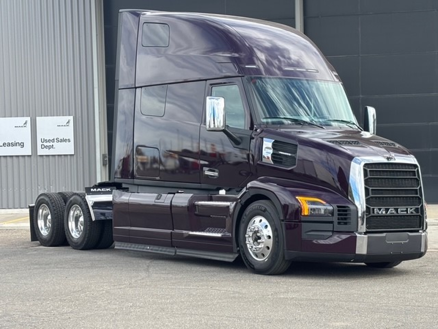 Mack PR64T76H Conventional Sleeper truck in dark maroon, 6x4 tractor, front grille with Mack badge, chrome bumper, side mirrors, two axles visible, cab with high sleeper, three rear axles.