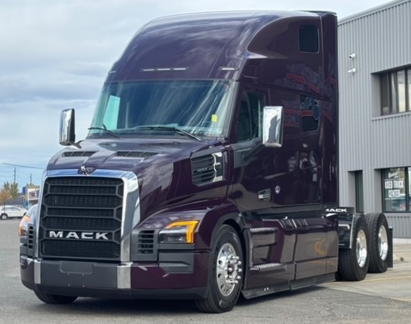 Mack PR64T76H tractor-trailer cab in dark purple showing front grille with Mack logo and headlights.