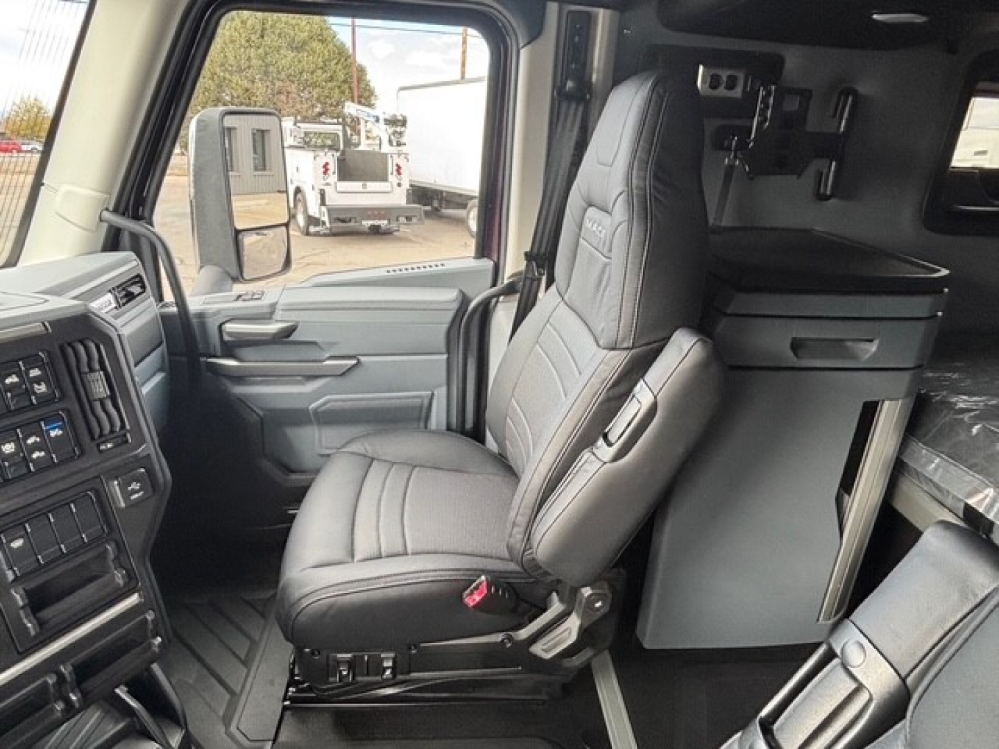 Truck cab interior showing driver seat and dashboard of a new Mack PR64T76H conventional sleeper