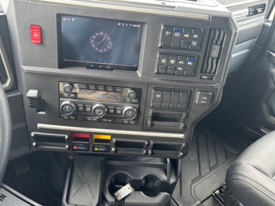 Cab interior of a 2026 Mack PR64T76H truck showing dashboard with touchscreen display, climate controls, switches, and cup holders.
