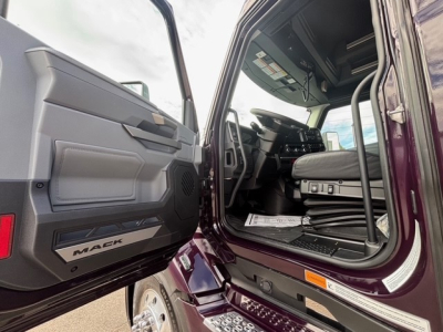 Cab interior of a 2026 Mack PR64T76H truck with door open, showing driver seat, dashboard, and entry step.