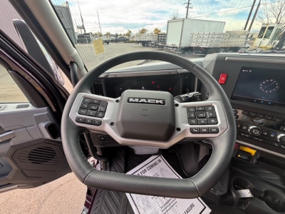 Mack PR64T76H truck interior steering wheel and dashboard showing control buttons and digital display.