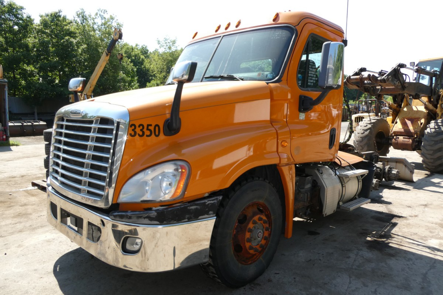 Orange Freightliner Cascadia 125 daycab truck in-service showing cab, front chrome grille, dual headlights, and wheel with orange rim.