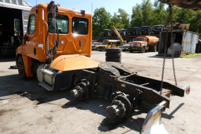 Freightliner Cascadia 125 truck chassis with orange cab, view of rear drivetrain and exposed axles.