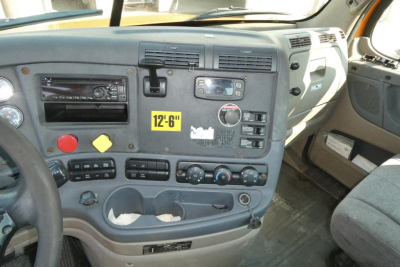 Dashboard and cockpit view of a Freightliner Cascadia 125 daycab showing instrument cluster, controls, and center console with yellow 12'6" height marker.