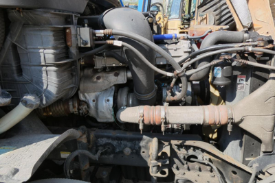 Truck engine bay with various hoses, tubes, and components visible in a Freightliner Cascadia 125 cab exterior side view.