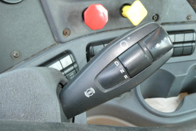 Gear shift lever with PRND indicators inside Freightliner Cascadia 125 cabin, with red and yellow control buttons in the background.