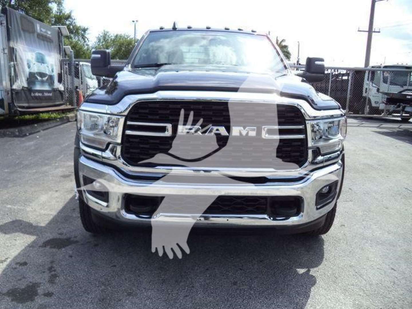 Front view of a 2024 Ram 5500 SLT truck in a dealership lot, chrome grille, RAM logo, large headlamps, flatbed category vehicle.