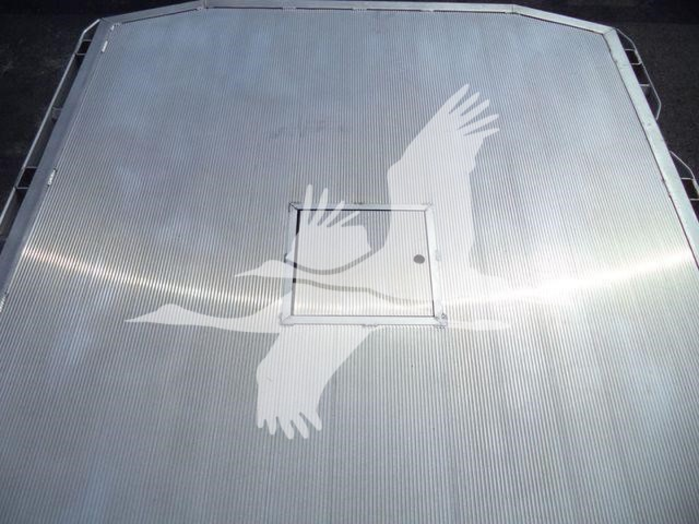 Aluminum truck bed hatch with decorative eagle wing pattern on a Ram 5500 flatbed showing a small square access panel.