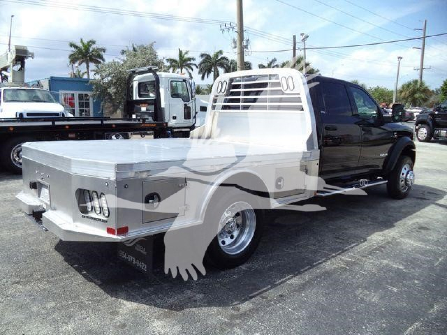 Ram 5500 flatbed truck in a dealership lot, rear and passenger side visible with flatbed cargo area and headache rack.