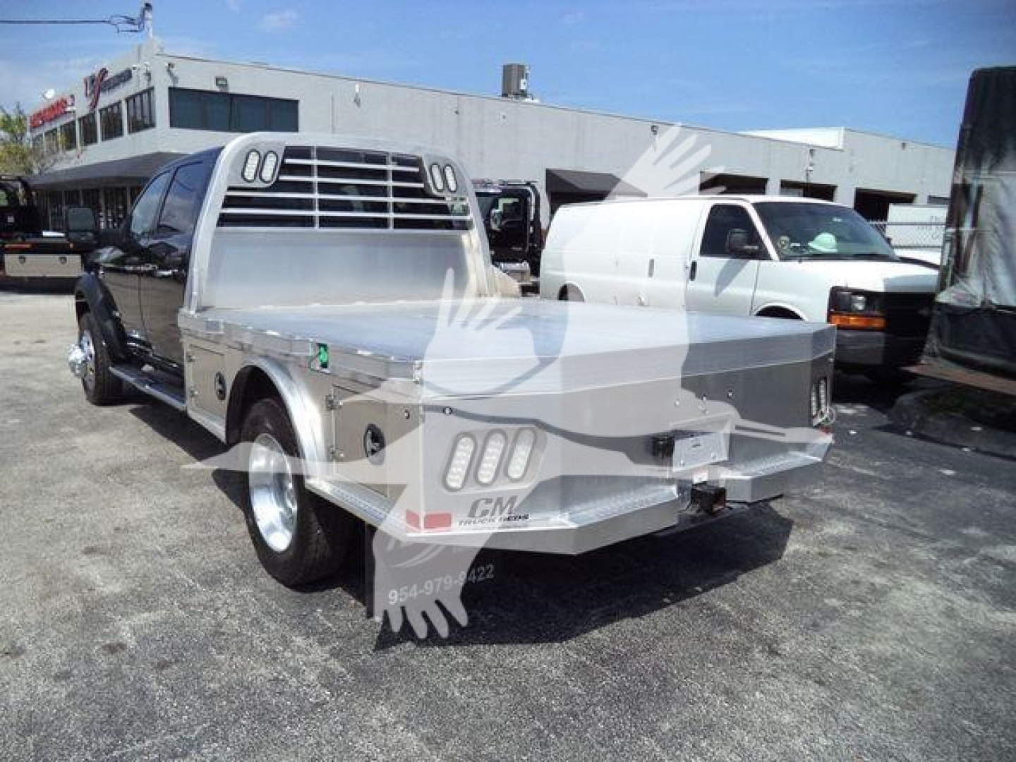 Ram 5500 SLT flatbed truck rear view showing aluminum flatbed with tailgate, dual rear wheels, and truck bed rails.