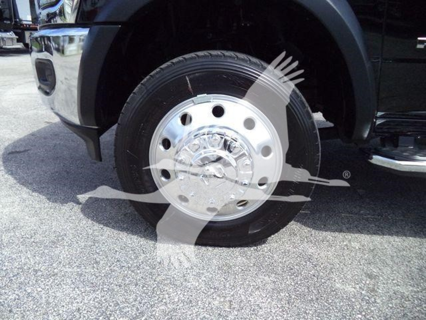 Wheel and front tire of a new 2024 Ram 5500 SLT in flatbed configuration showing chrome hubcap and tire tread.