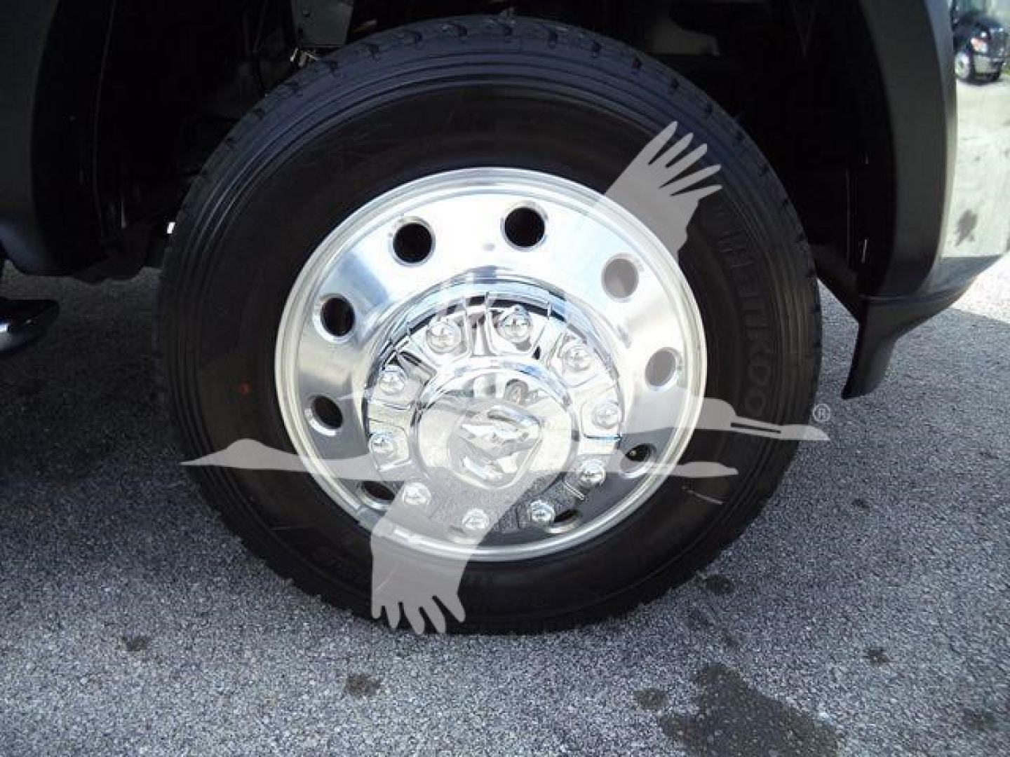 Ram 5500 SLT wheel and tire assembly; chrome hubcap with lug nuts visible; tire mounted on steel wheel with circular holes; front wheel well and fender in view.