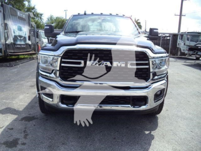 Front view of a 2024 Ram 5500 SLT truck in a dealership lot, chrome grille, RAM logo, large headlamps, flatbed category vehicle.