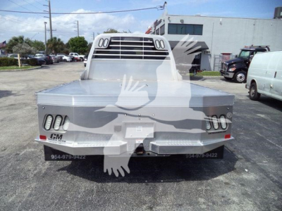 Ram 5500 flatbed truck seen from rear, with dual rectangular taillights on each side, aluminum flatbed, CM logo on bumper, and rear window guard.