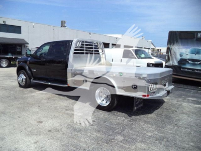 Ram 5500 SLT flatbed truck in a dealership lot, black cab with a silver flatbed and metal headache rack.