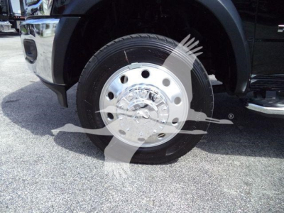 Wheel and front tire of a new 2024 Ram 5500 SLT in flatbed configuration showing chrome hubcap and tire tread.