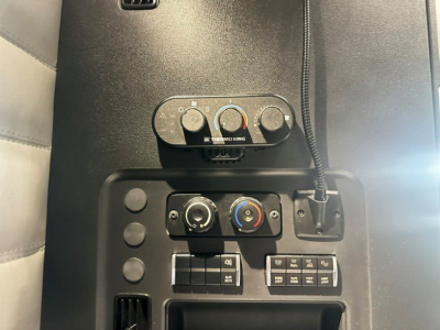 Cabin controls and climate panel of a Freightliner Cascadia 126 truck cab with HVAC knobs and switches visible.