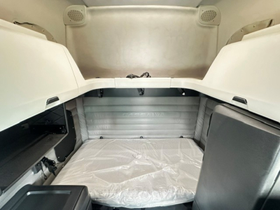 Freightliner Cascadia 126 sleeper cab interior showing cargo area with plastic-covered bed and side storage shelves.