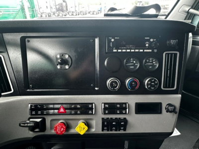 Cab dashboard of a Freightliner Cascadia 126 truck showing control panels, gauges, radio, hazard button, and switch panels.