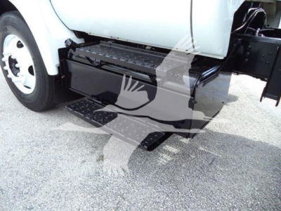 Ford F650 dump truck side view showing black underbody toolbox and step; visible fuel/air lines and wheel on left; white cab with black step area.