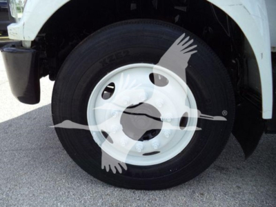 Truck front wheel and fender of a 2017 Ford F650 dump truck showing front tire and white wheel with hub and wheel well.