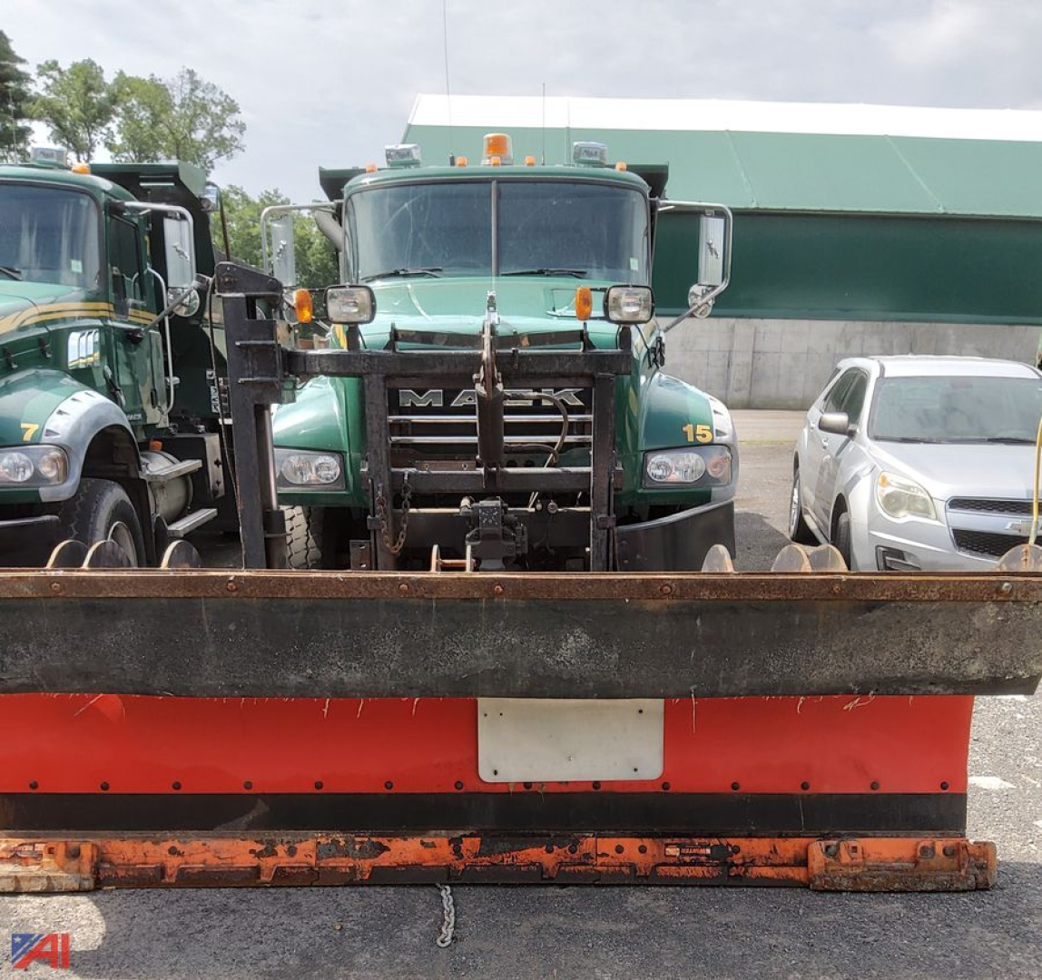 Mack Granite dump truck with snow plow attachment in front, green cab with orange beacon, plow blade and mounting hardware visible.