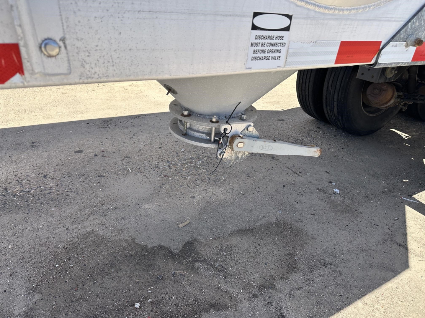 Trailer hitch/landing gear area of a 2012 Polar gravity drop pneumatic trailer showing mounting hardware and underside of body, with pin and chain visible.