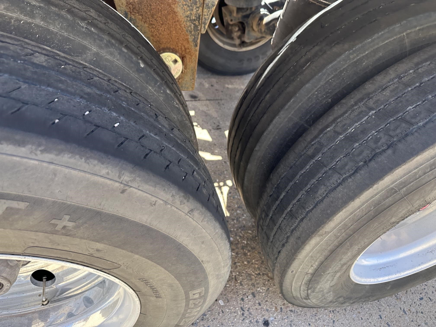 Trailer wheel area showing two large pneumatic tires and rims, with rusted frame behind; part of a Polar gravity drop pneumatic trailer.