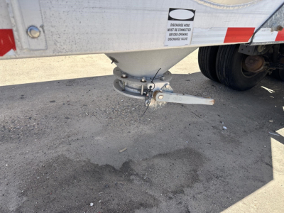 Trailer hitch/landing gear area of a 2012 Polar gravity drop pneumatic trailer showing mounting hardware and underside of body, with pin and chain visible.