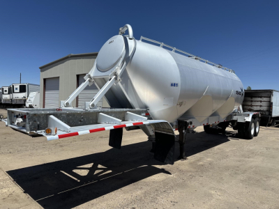 Polyethylene tank trailer for dry bulk with rear gravity drop pneumatic system, 3-hop air ride suspension, cylindrical stainless tank, front ladder structure, side access manway, treaded landing gear, blue sky.
