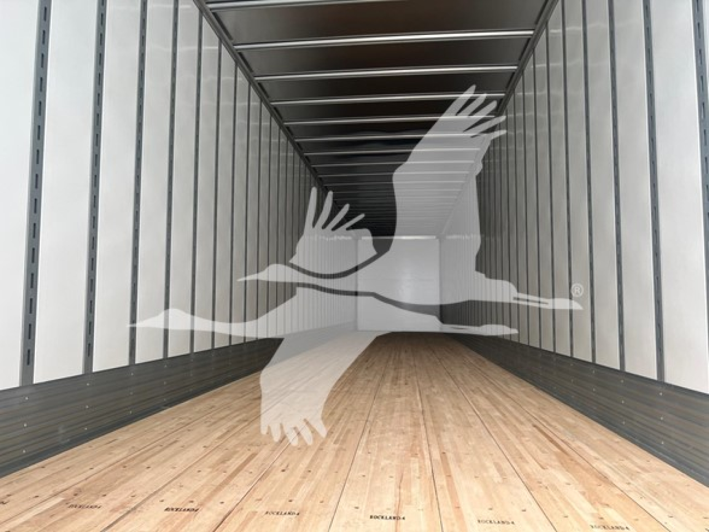 Inside view of a Vanguard sheet/post trailer trailer bed with wooden floor and metal side rails, empty cargo area.