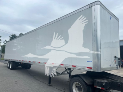 Trailer side showing a large white graphic of flying birds. Box trailer with silver aluminum panels and support legs in front. No visible model numbers or text besides graphic.