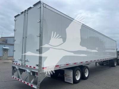 Trailer side and rear view showing a silver Vanguard sheet trailer with dual rear wheels, metal doors, and safety reflectors; VIN 5V8VA5327VM605644 and stock VM605644 visible.