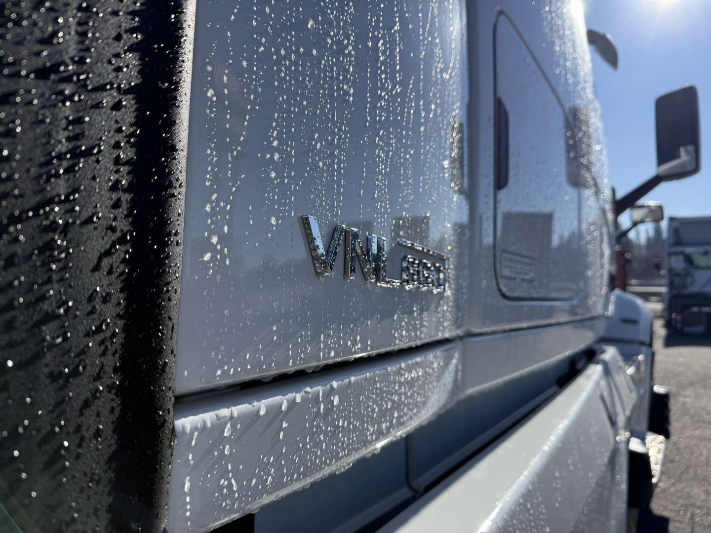  Volvo VNL cab side with VNL badge and rain droplets on the door in a truck lot.