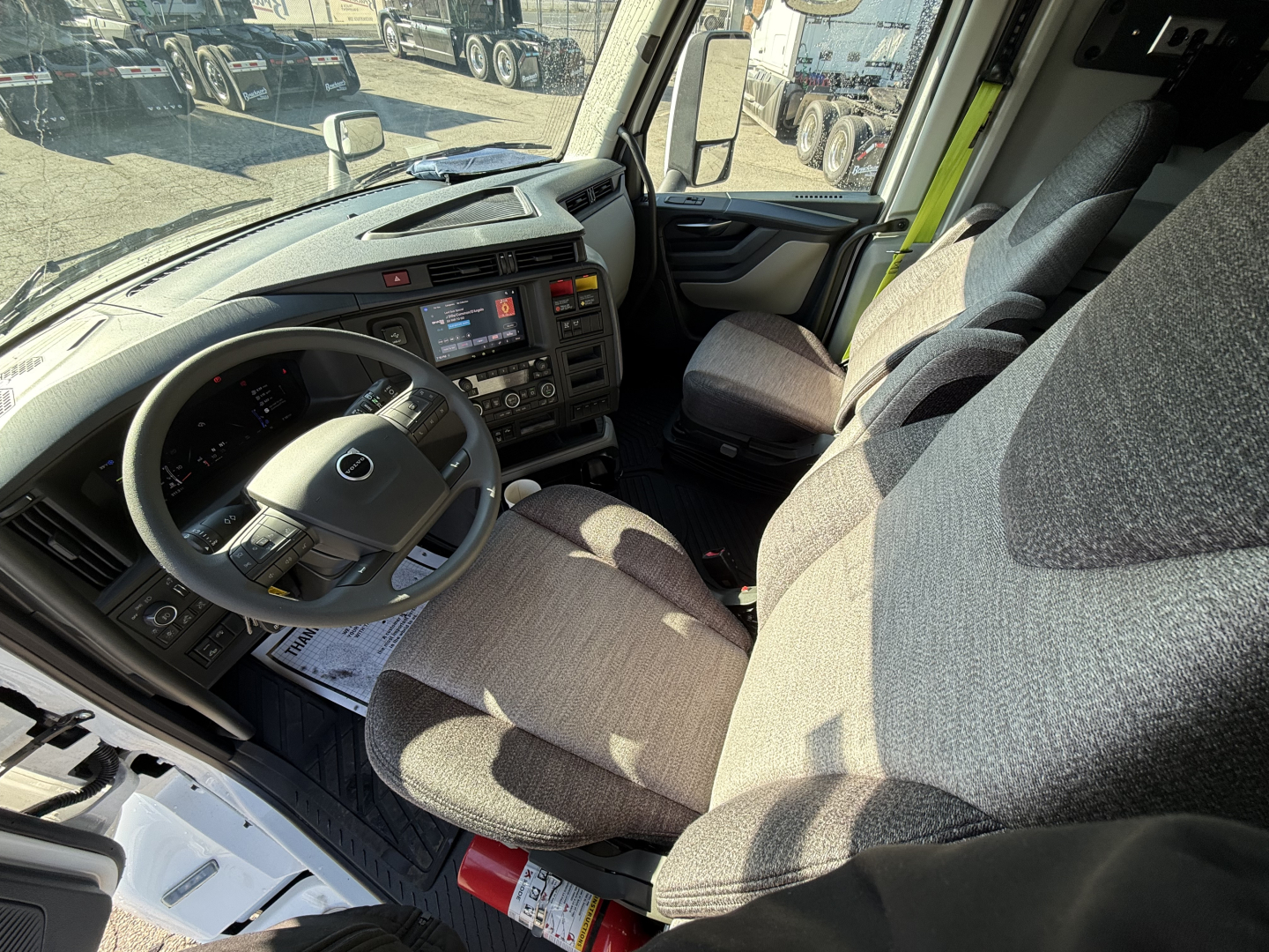 Volvo VNL64T860 truck interior showing driver seat, steering wheel with Volvo logo, dashboard with digital displays, and passenger seat. 