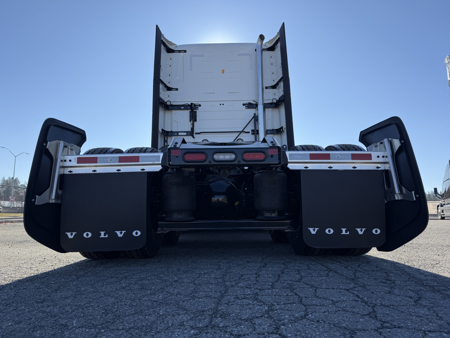 Volvo VNL64T860 rear view showing dual rear wheels, mud flaps with Volvo logo, and flatbed/tractor configuration.
