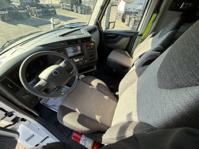 Volvo VNL64T860 truck interior showing driver seat, steering wheel with Volvo logo, dashboard with digital displays, and passenger seat. 