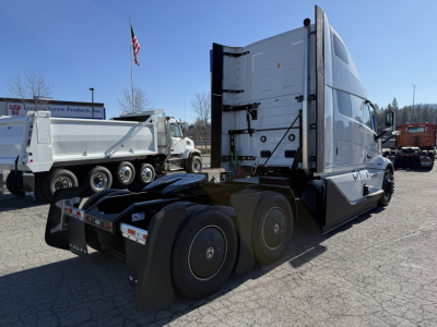 Volvo VNL64T860 tractor from rear-left side showing sleeper cab, tandem axle, and fifth wheel with aluminum fuel tanks and rear lights.