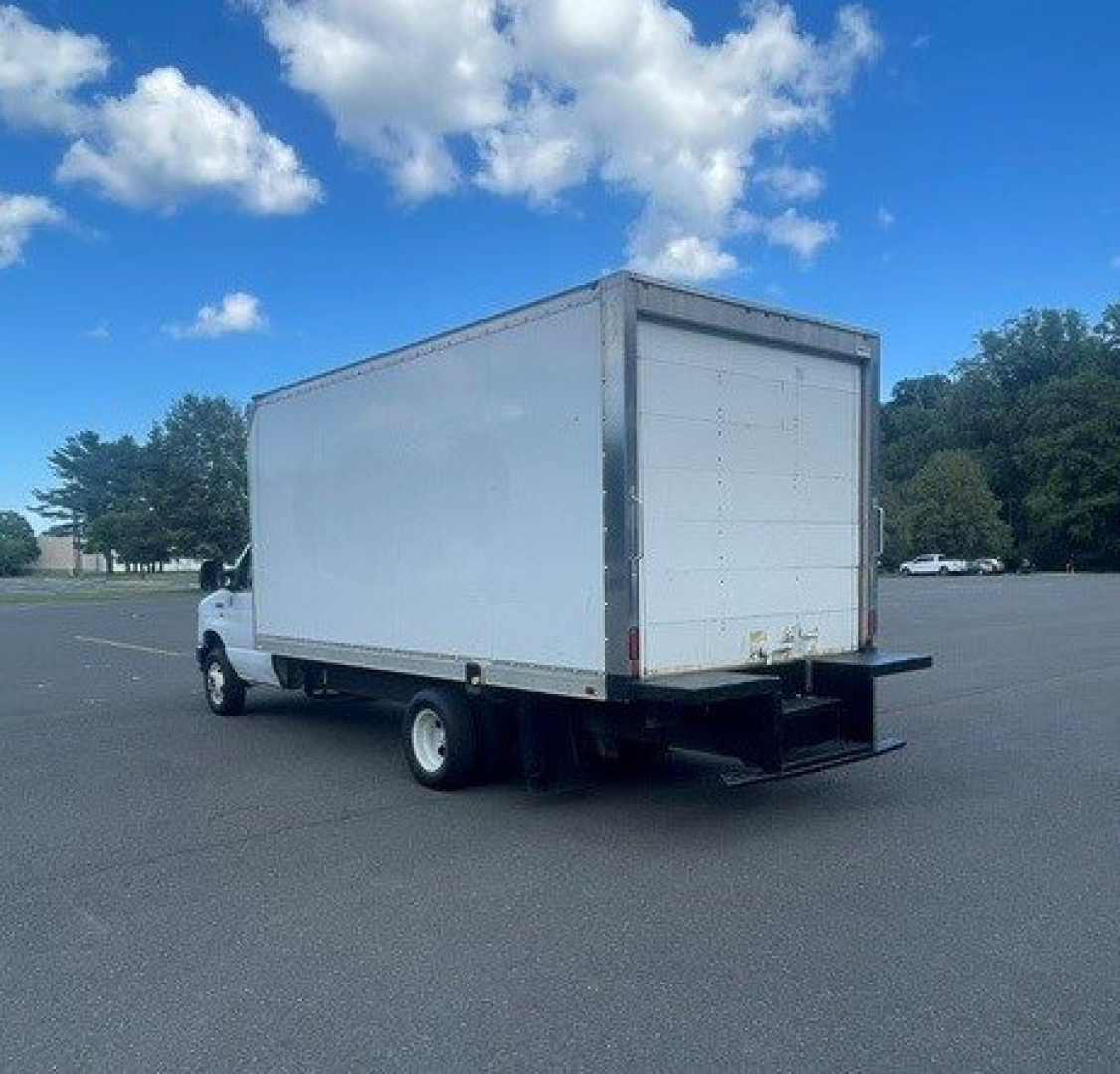 Truck cab chassis with a large white box cargo area on a Ford E-Series Cutaway, rear garbage-style ramp and black rear bumper.
