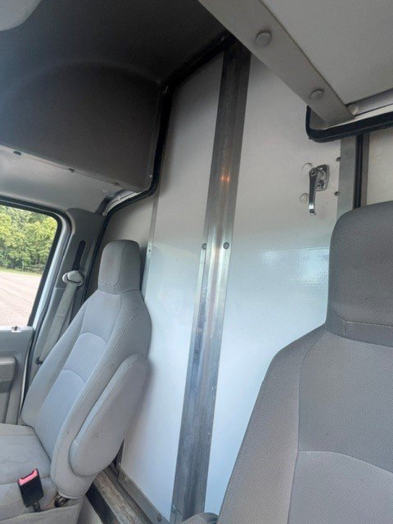 Ford E-Series Cutaway cab interior with partition wall and driver/passenger seats; vertical metal divider; window and door trim visible.
