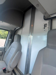 Ford E-Series Cutaway cab interior with partition wall and driver/passenger seats; vertical metal divider; window and door trim visible.