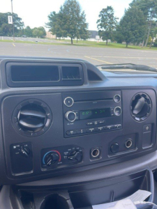 Dashboard of a 2019 Ford E-Series Cutaway showing circular HVAC vents, radio, and climate controls.