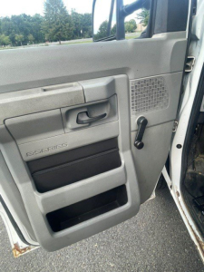 Ford E-Series Cutaway door panel showing manual window crank, storage pockets, and S-Series badge on the interior door, along with vent grid.
