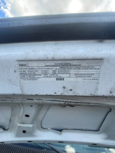 Ford E-Series Cutaway Vin plate showing vehicle emission information label under open hood area.
