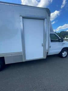 Ford E-Series Cutaway truck with a rear refrigerated body door on the side, white cab, door frame, and metal clad paneling.