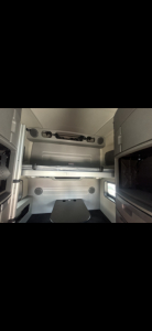 Volvo VNL64T860 sleeper cab interior showing side shelves and upper storage with windowed bulkhead.