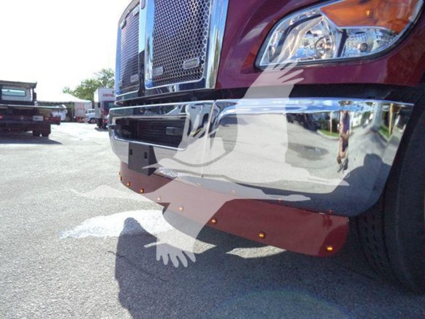 Kenworth T280 front bumper and chrome grille with red body, lower red mud flaps, and bumper reflectors visible.